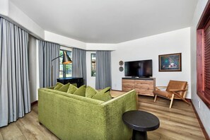 Een moderne woonkamer met een groene bank, een houten kast, een televisie en een schilderij aan de muur.