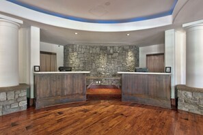 Un área de recepción con pared de piedra, mostrador de madera y suelo de madera en patrón de espiga.