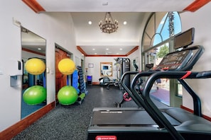 Un gimnasio con cintas de correr, pelotas de ejercicio y un espejo.
