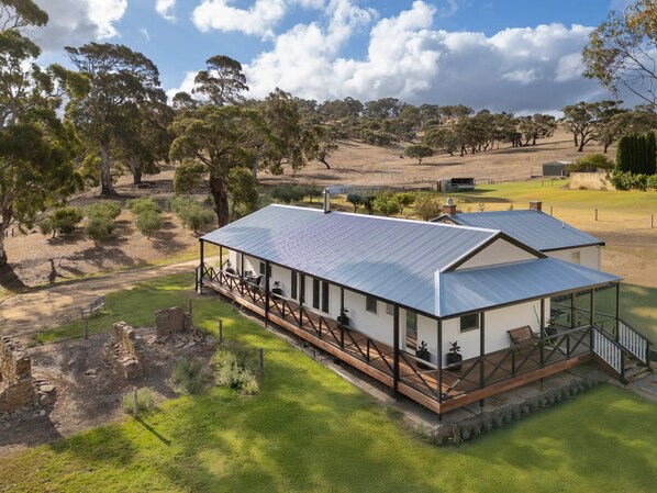 A modern house with a metal roof, surrounded by a grassy area and trees.