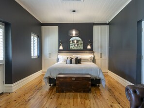 A bedroom with a large bed, wooden flooring, and a bench.