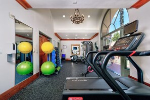 Ein Fitnessraum mit Laufbändern, Übungsbällen und einem Spiegel.