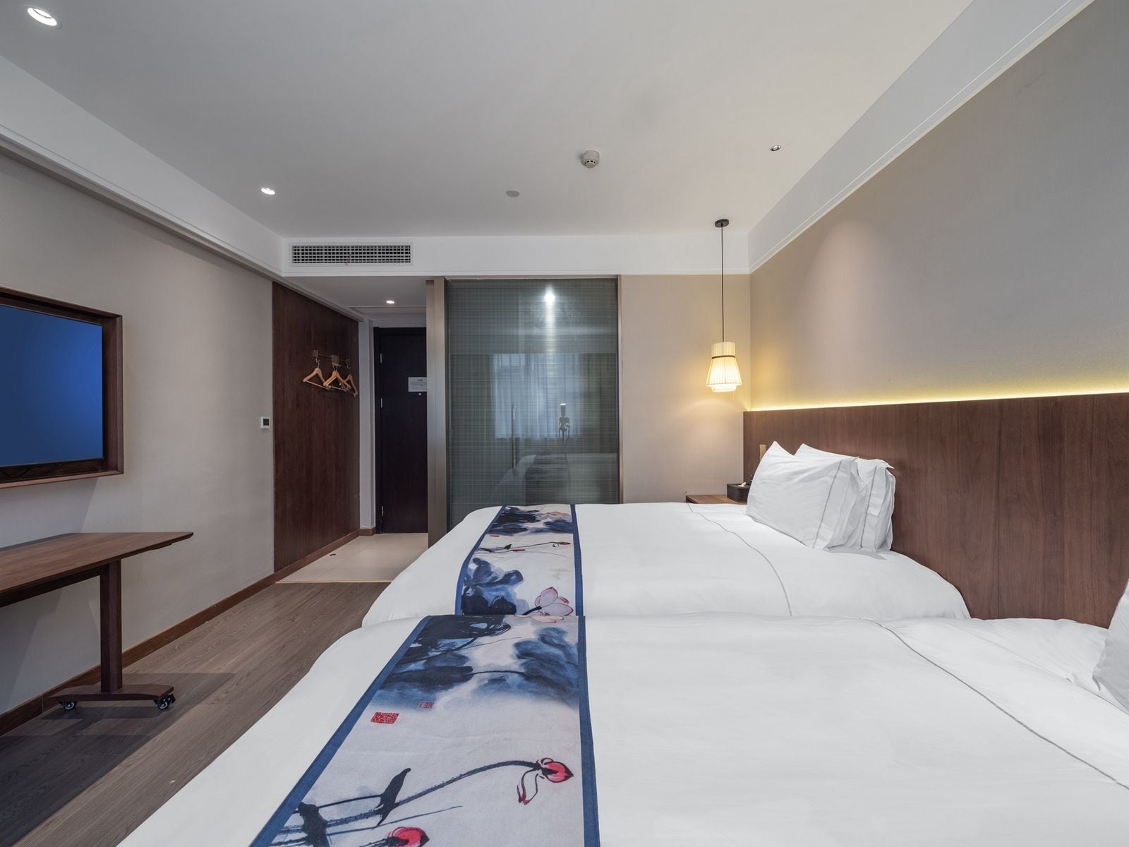 A hotel room with a bed, a TV, a desk, and a wardrobe.