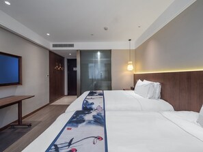 Quarto de hotel com cama, televisão, escrivaninha e guarda-roupa.