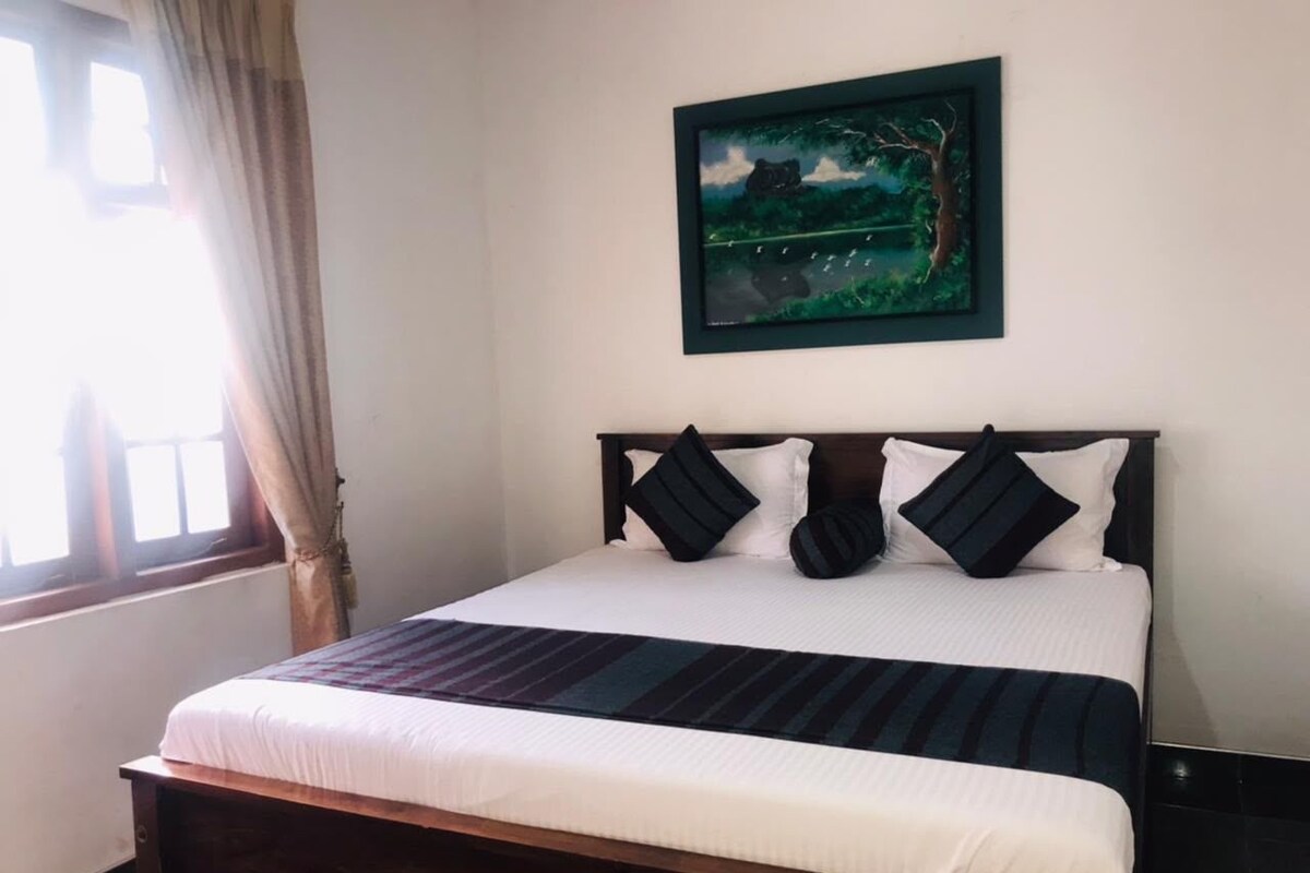 A bed with a dark headboard, white bedding, and a striped blanket.