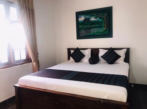 A bed with a dark headboard, white bedding, and a striped blanket. - Forest Villa Nature Resort  (Anuradhapura)
