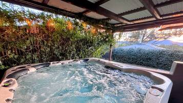 Un bain à remous avec un décor en bambou et une vue sur l’extérieur.
