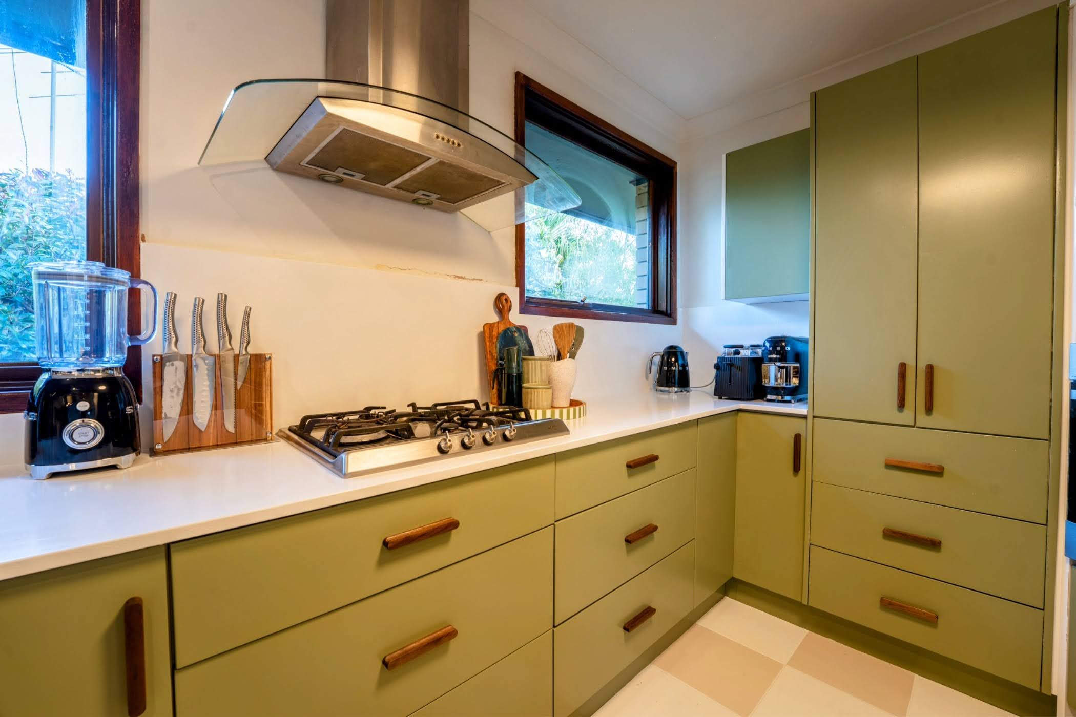 A kitchen with a gas stove, a blender, and various utensils.
