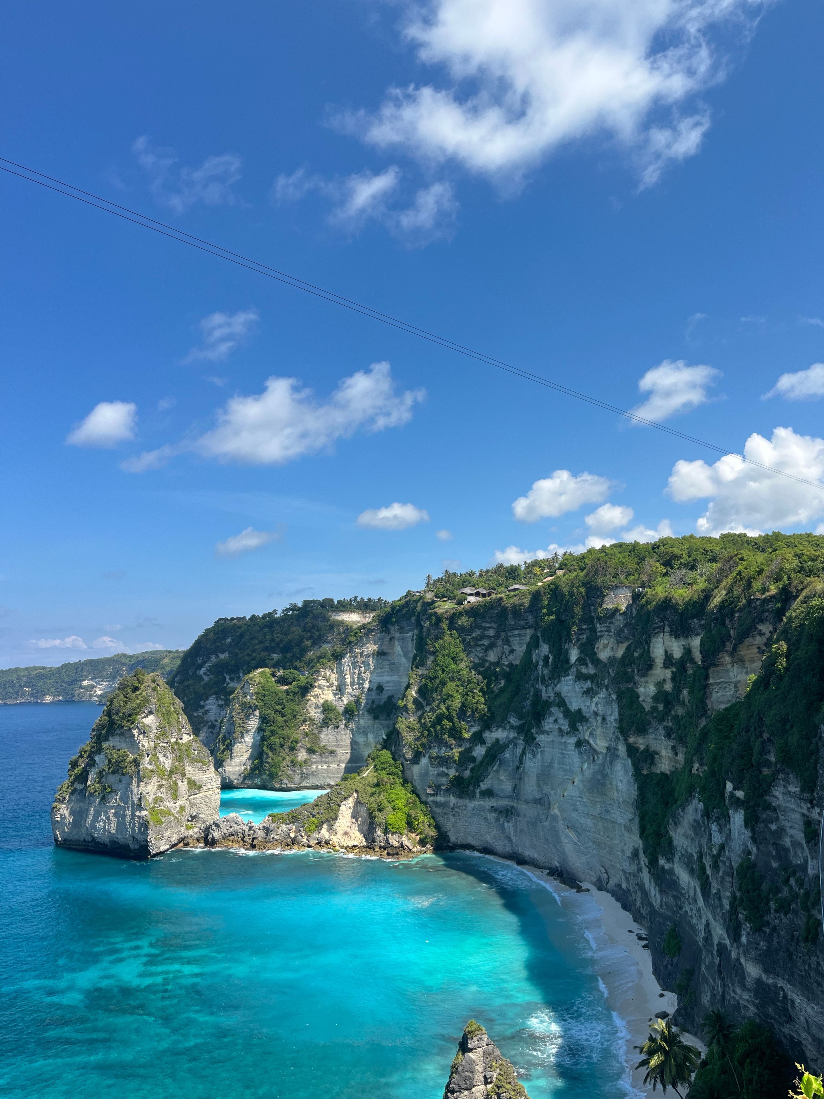 Paisagem costeira com falésias, águas azul-turquesa e céu claro.