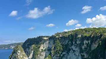 Paisagem costeira com falésias, águas azul-turquesa e céu claro.