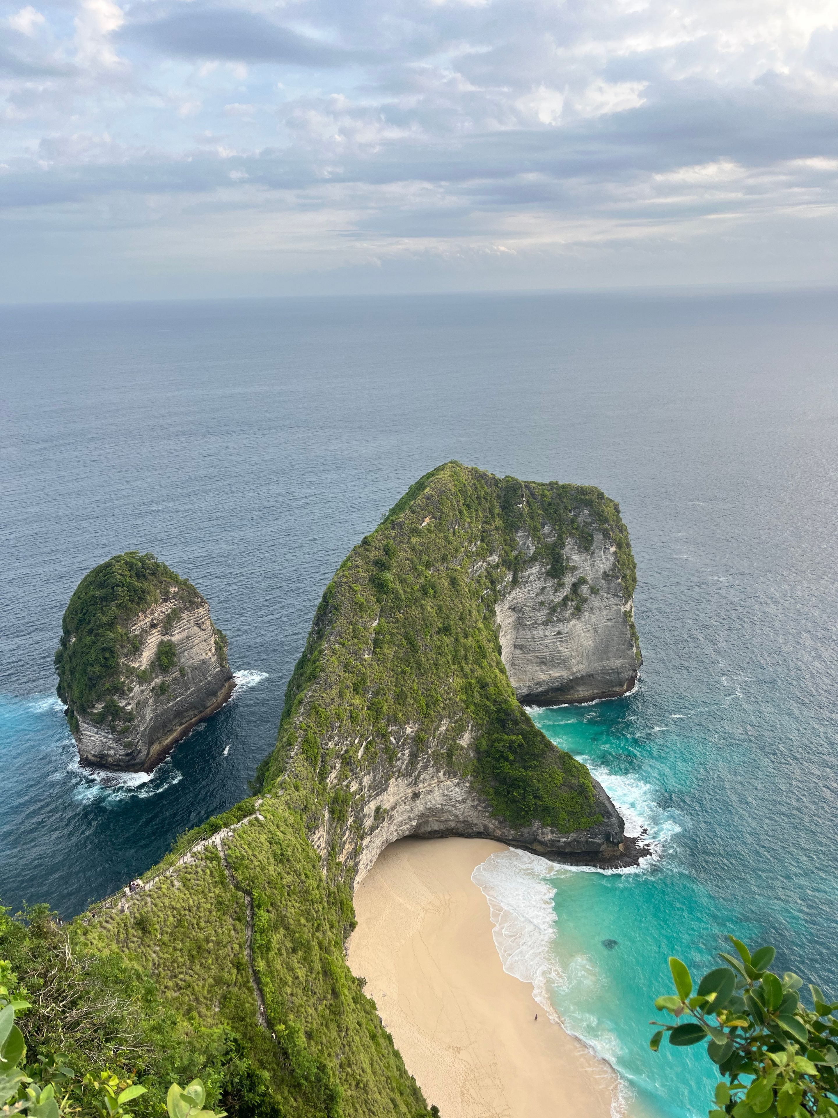 A coastal landscape with a prominent rock formation and a sandy beach.