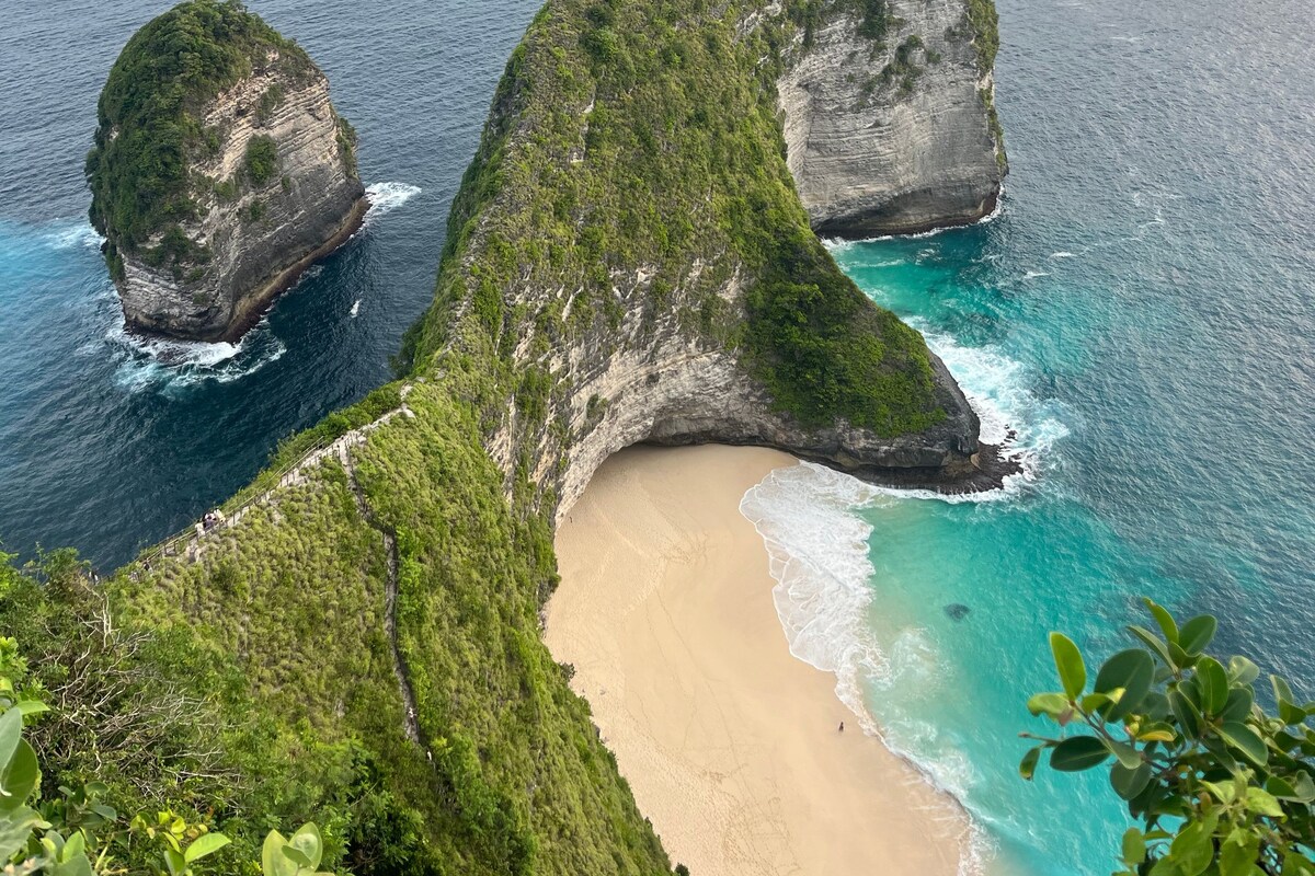 Paisagem costeira com uma formação rochosa imponente e uma praia arenosa.
