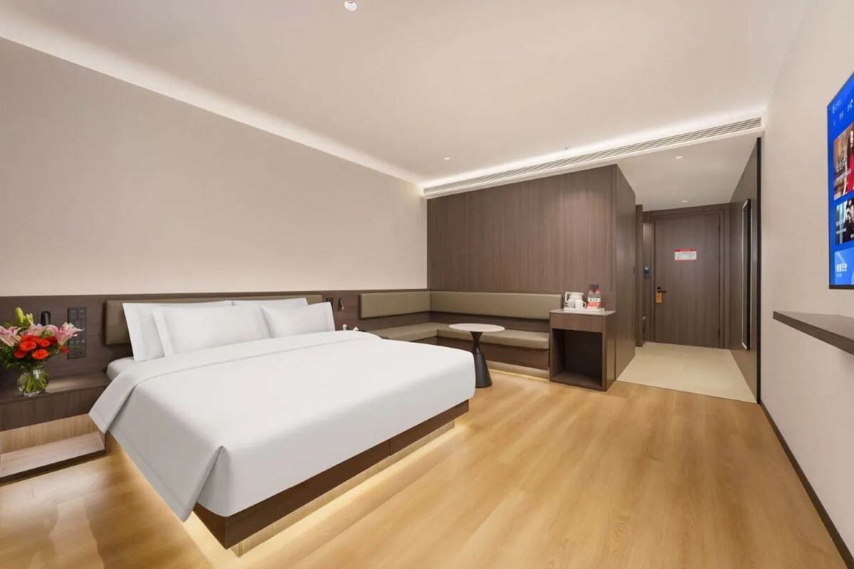 Une chambre d’hôtel moderne équipée d’un lit, d’une table de chevet et d’un petit bureau.
