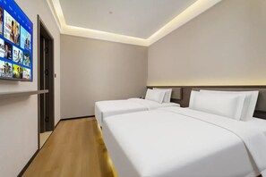 Une chambre d’hôtel avec deux lits, un téléviseur fixé au mur et un plancher en bois.