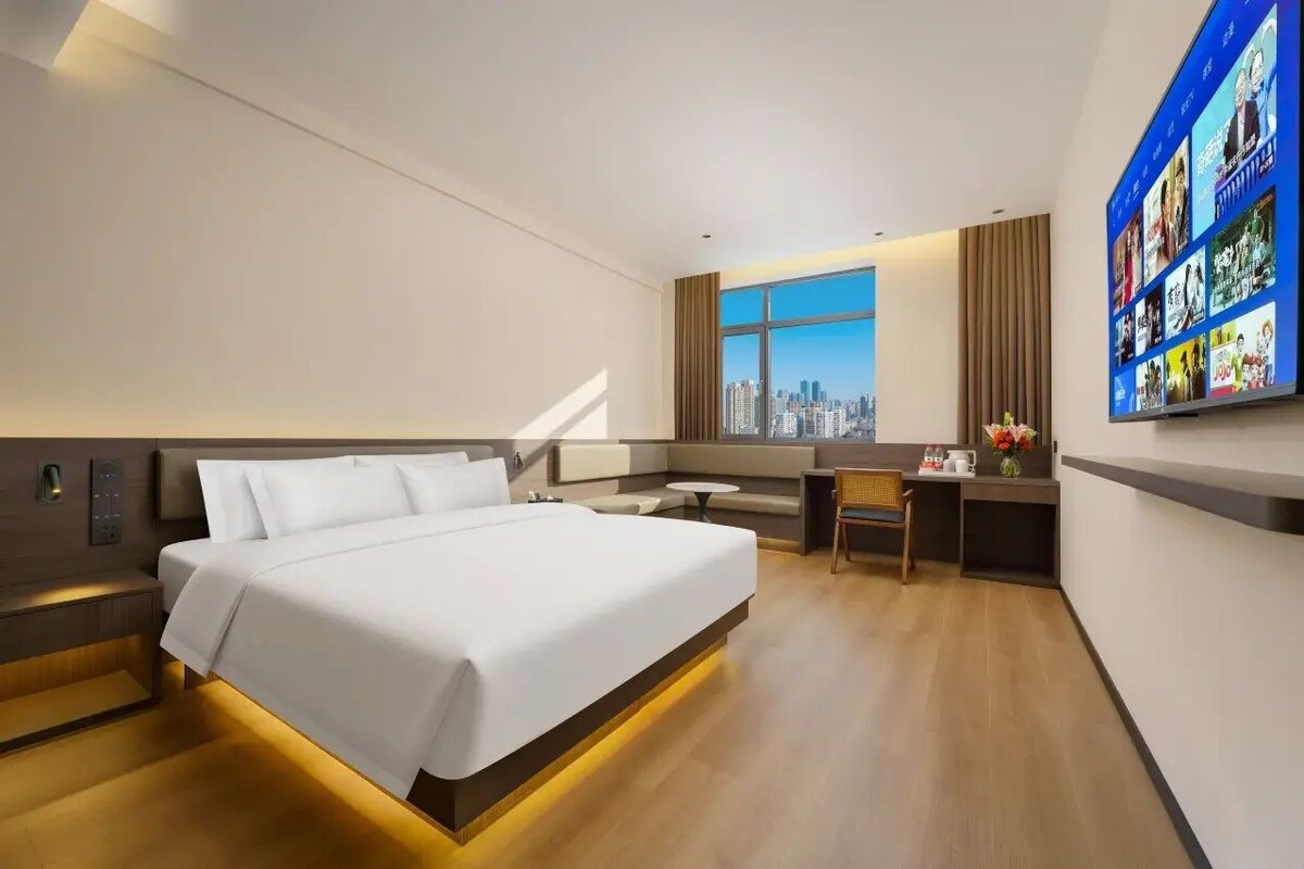 Une chambre d’hôtel moderne avec un grand lit, un bureau et une vue sur la ville.