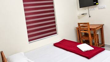 Une chambre d’hôtel équipée d’un lit, d’une télévision, d’une fenêtre avec stores et d’un appareil de climatisation.