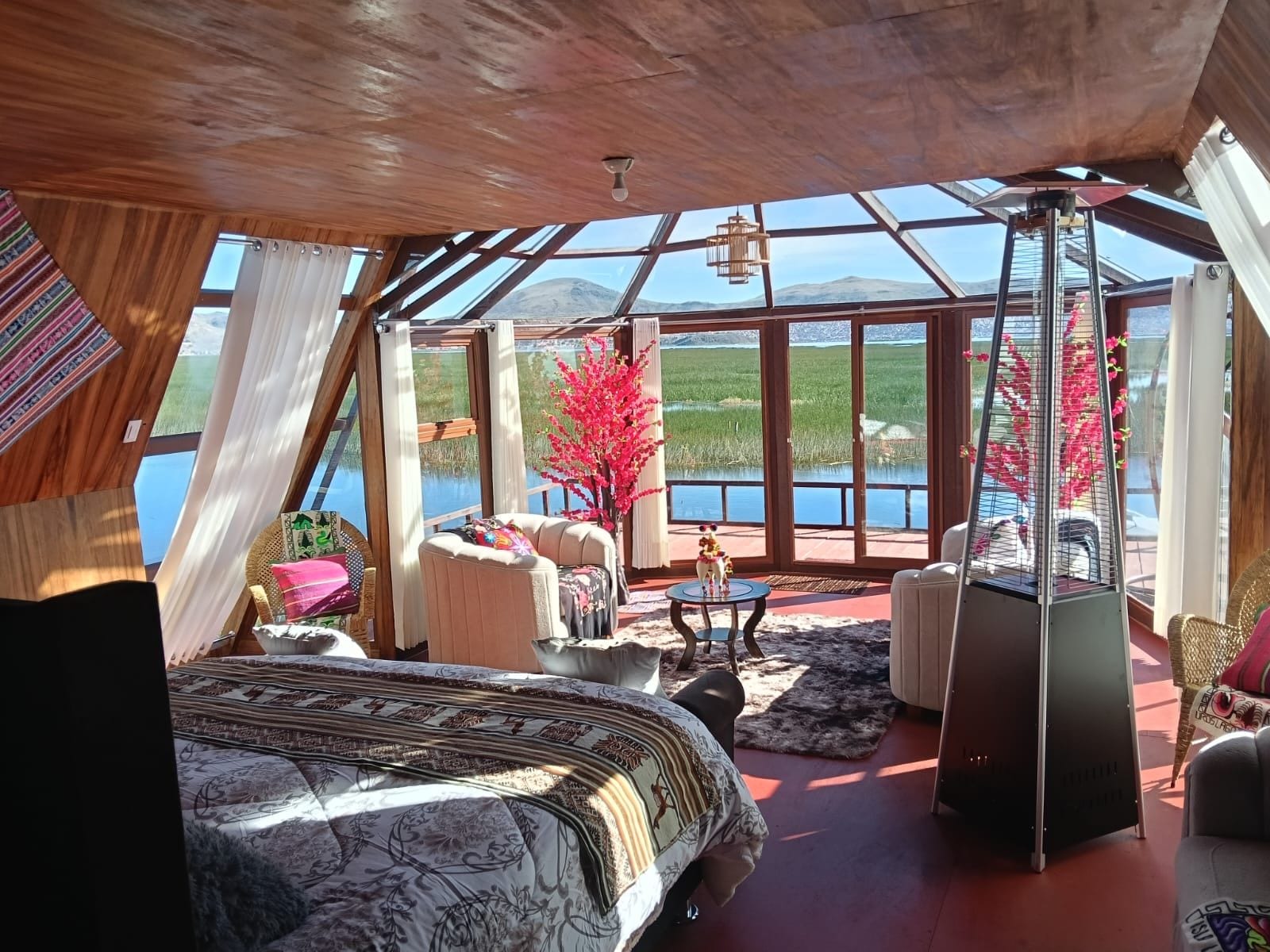 A spacious room with a large bed, a seating area, and a view of a lake and mountains.
