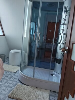 A glass-enclosed shower area with a white base, a small step, and a metal door handle. - Titicaca Lake House Peru (Puno)