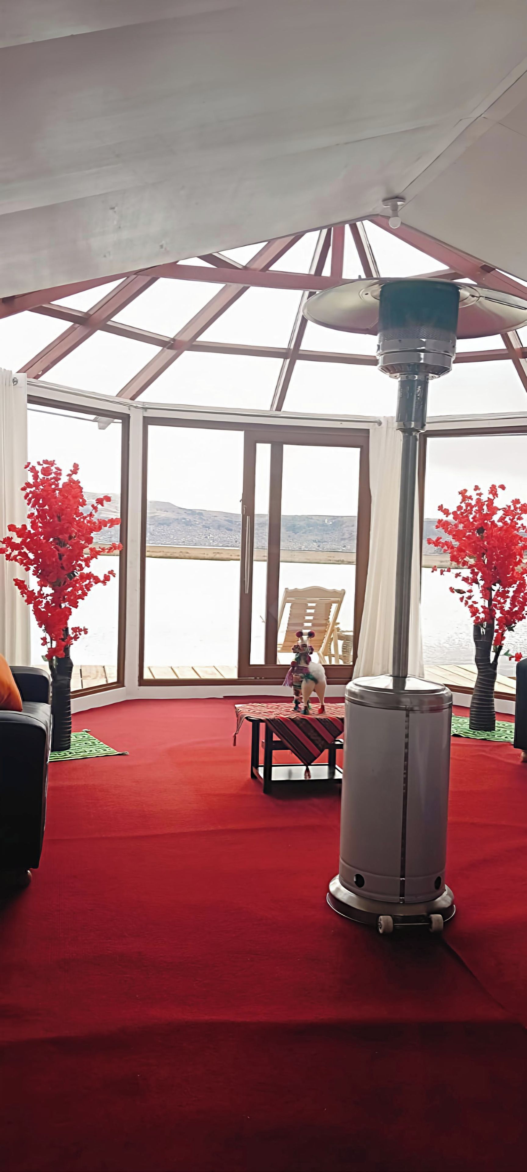 Una habitación con alfombra roja, una mesa, sillas y vistas al agua.