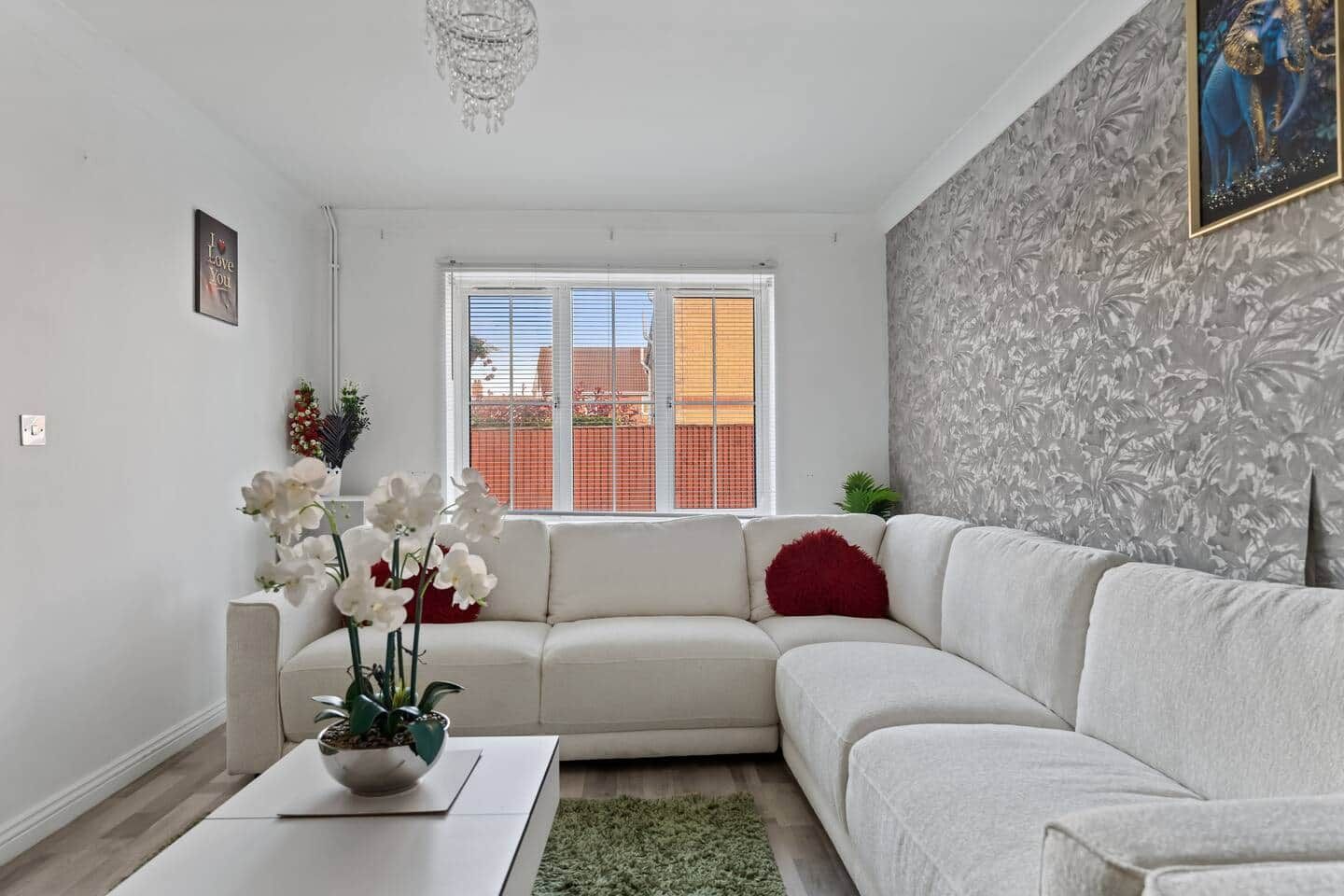 Un salon moderne avec un canapé blanc, une table basse et une plante décorative.