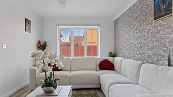 Un salon moderne avec un canapé blanc, une table basse et une plante décorative.