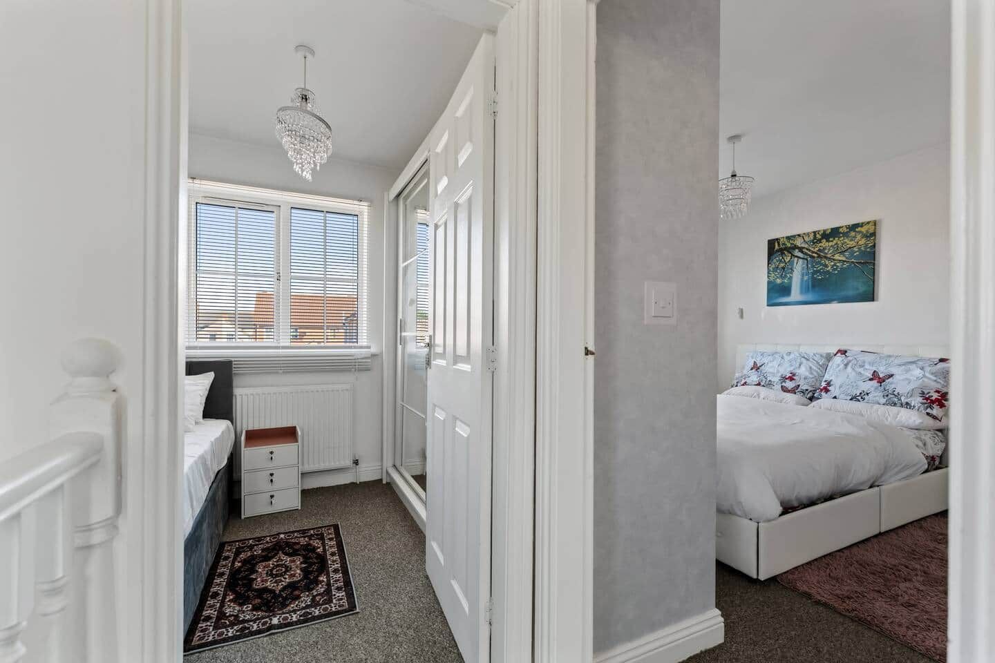 Een slaapkamer met een bed, een radiator, een raam met jaloezieën, een deur en een schilderij aan de muur.