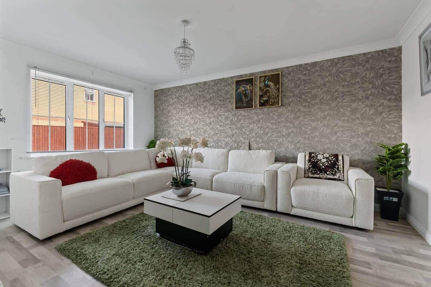 Een moderne woonkamer met een hoekbank, een salontafel en een decoratieve plant.