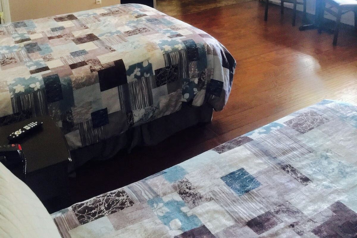 Een bed met een sprei en een houten vloer.