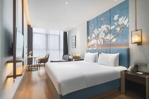Une chambre d’hôtel avec un grand lit, un bureau, une chaise et un tableau au mur.