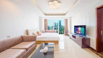 Ein modernes Hotelzimmer mit Bett, Sofa, Fernseher und Blick auf die Stadt.
