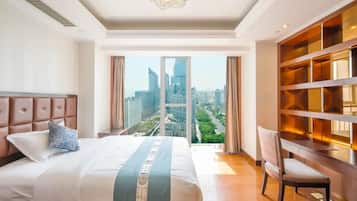 A hotel room with a large bed, a view of the cityscape, a bookshelf, and a desk.