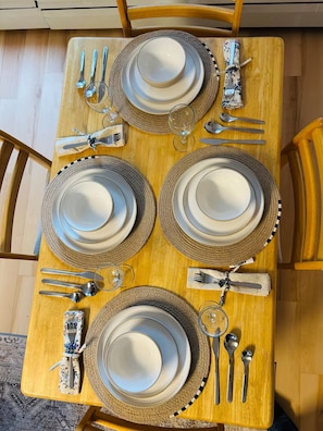 A dining table set with four plates, cutlery, and glasses, surrounded by chairs. - Private suite near trails with mountain view (North Vancouver)