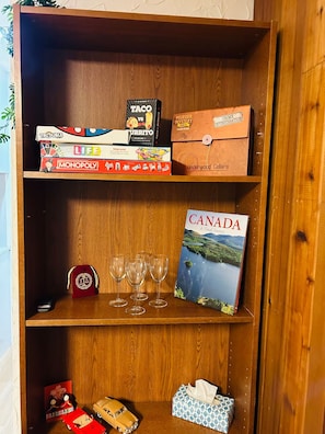 A wooden shelf with various board games, a book titled 'Canada: A Visual Journey,' and a tissue box. - Private suite near trails with mountain view (North Vancouver)