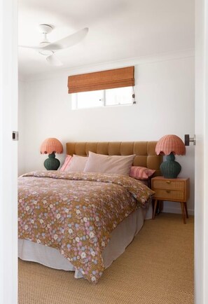 A bedroom with a bed, bedside lamps, a window with a blind, and a ceiling fan. - Kleopatra Retro Coastal Luxury with Ocean Views (Sunshine Coast)