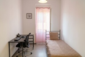 A small, tidy room with a bed, a desk with a chair, and a window with a curtain. - New Listing (Digne-les-Bains)