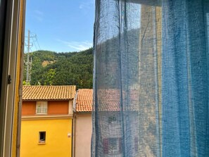 A window with a view of a building with a tiled roof and a yellow wall. - New Listing (Digne-les-Bains)