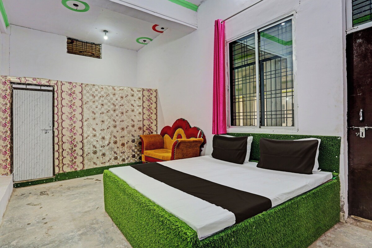 A bedroom with a bed, a window with a curtain, a door, and a patterned wall.