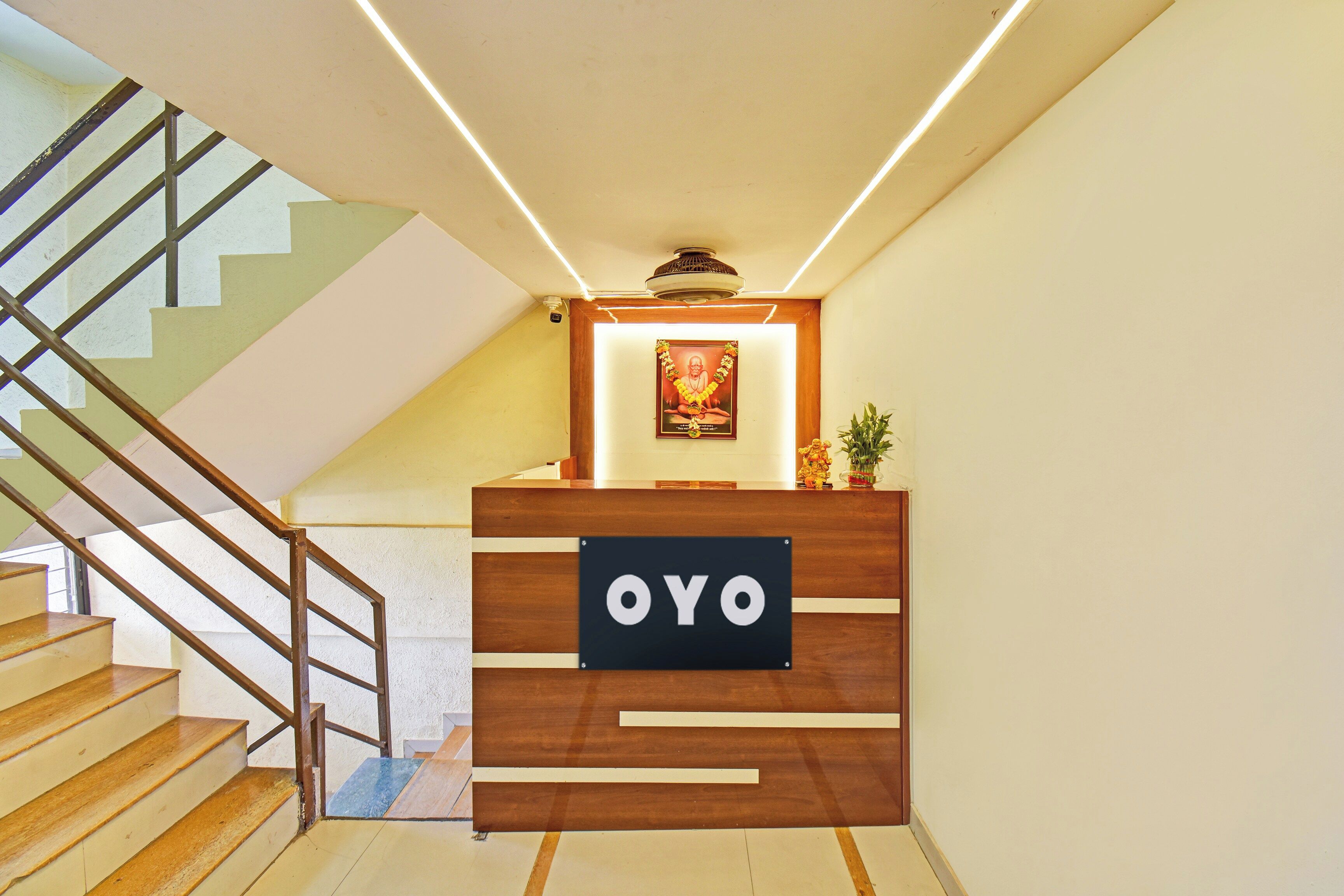 Un comptoir d'accueil avec une enseigne indiquant « OYO », situé dans un intérieur moderne agrémenté d'un escalier et d'un ventilateur de plafond.