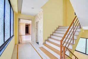A staircase with wooden steps and metal railings, leading to a landing with a door. - Hotel O RVC GRAND CENTRAL (Pune)
