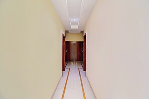 A hallway with a ceiling light, a door at the end, and a floor with a yellow line. - Hotel O RVC GRAND CENTRAL (Pune)