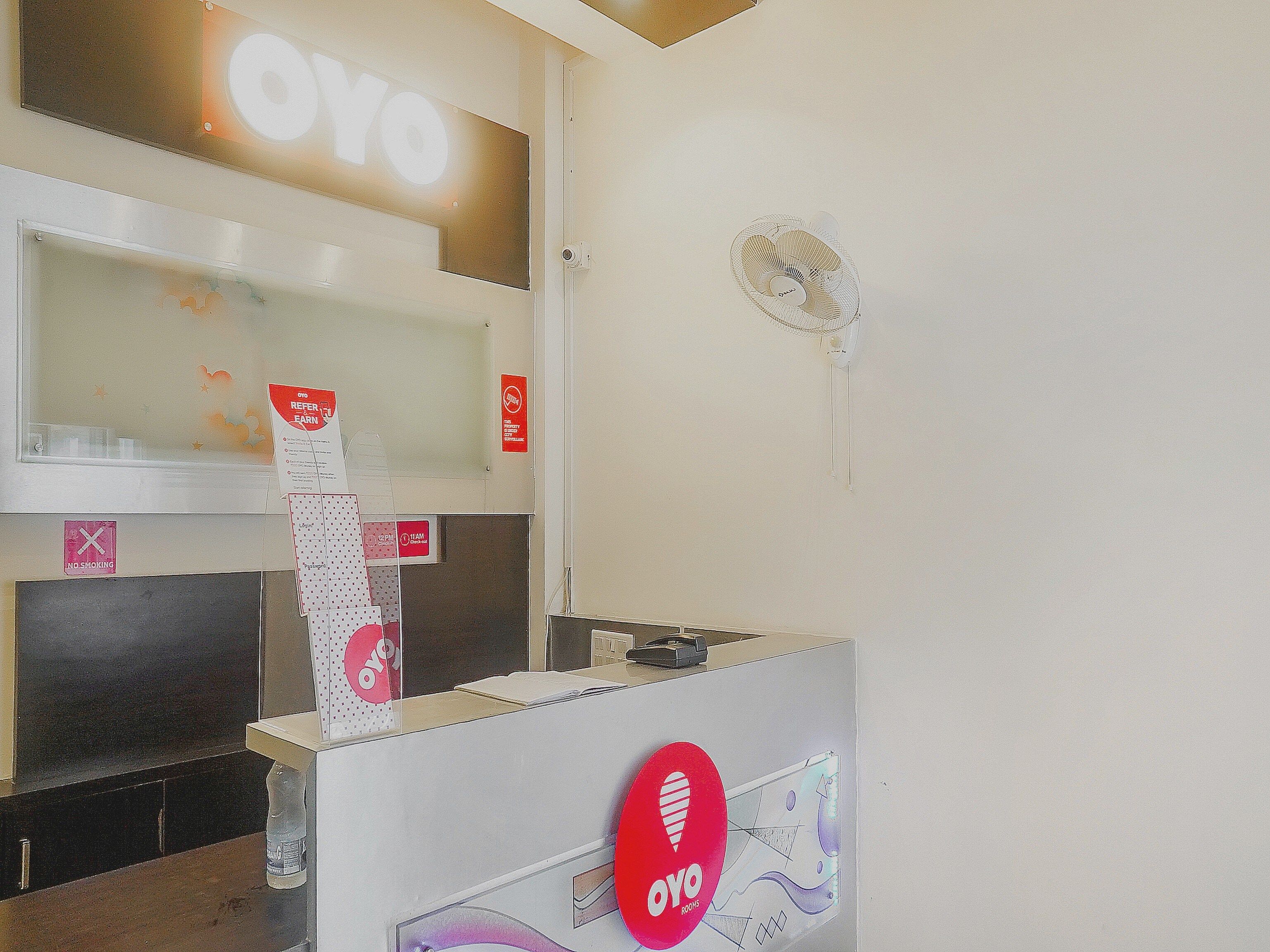 A reception desk with a 'YO' sign, a no-smoking sign, and a fan on the wall.