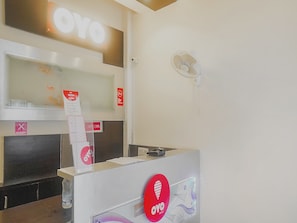 A reception desk with a 'YO' sign, a no-smoking sign, and a fan on the wall. - Hotel O Paradise Inn Talegaon Dabhade (Mawal)