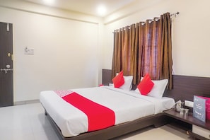 A hotel room with a bed, a nightstand, a lamp, and a curtain. - Hotel O Paradise Inn Talegaon Dabhade (Mawal)