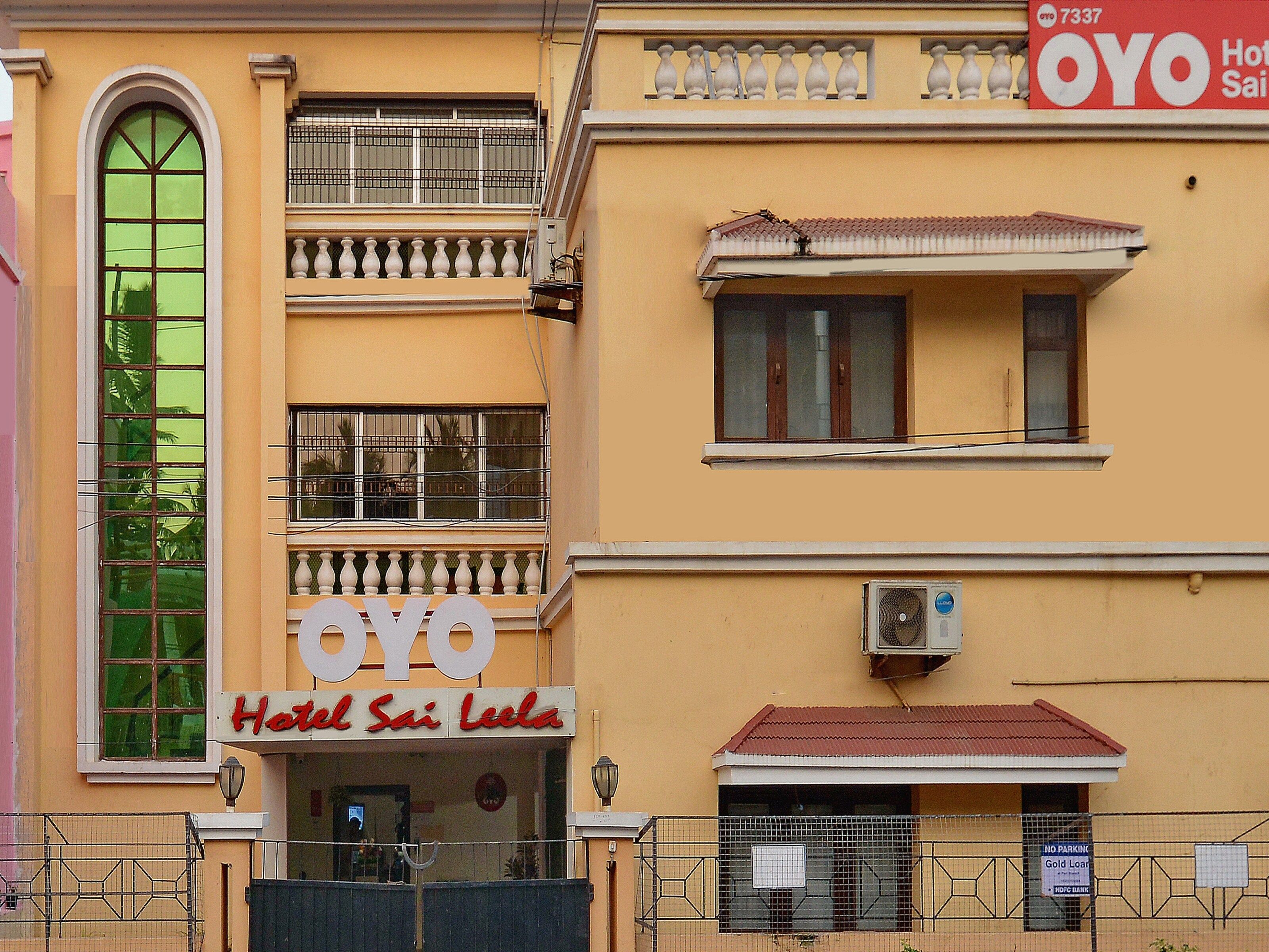 Un hotel con un letrero visible que dice 'OYO Hotel Sai Leela' y un balcón con barandillas blancas.