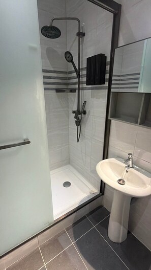 A bathroom with a glass-enclosed shower, a white sink, and a mirror. - The Heart of Punda King Studio (Willemstad)