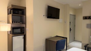 A hotel room with a kitchenette, a television mounted on the wall, and a desk with a chair. - The Heart of Punda King Studio (Willemstad)