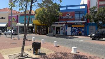 Vista de la calle con varias tiendas, incluyendo una tienda de electrónica visible.