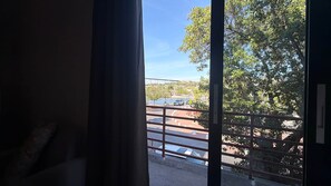 A view from a window with a metal railing, overlooking a paved area with trees and a bridge in the distance. - The Heart of Punda King Studio (Willemstad)