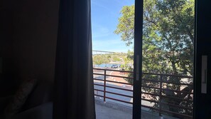 A room with a view of a bridge, trees, and parked cars through a window with a metal railing. - The Heart of Punda Studio 2 King Size beds (Willemstad)