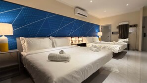 Habitación de hotel con dos camas, una pared de diseño geométrico azul, un equipo de aire acondicionado y una puerta con perchero.
